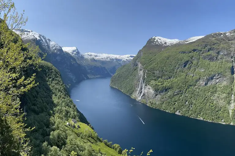 The deep blue waters of Geirangerfjord cutting between forested mountain walls